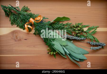 Gros plan d'un paquet d'herbes médicinales fraîches attachées avec un ruban orange et placées sur une planche de cèdre, utilisée par les Premières Nations Banque D'Images