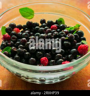 Diverses baies dans une plaque de verre. Baies rouges sur une table en bois. Belle composition de baies. Banque D'Images