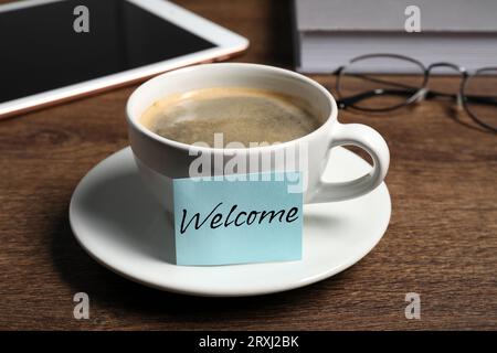 Note collante avec mot Bienvenue attaché à la tasse de café sur le bureau en bois Banque D'Images