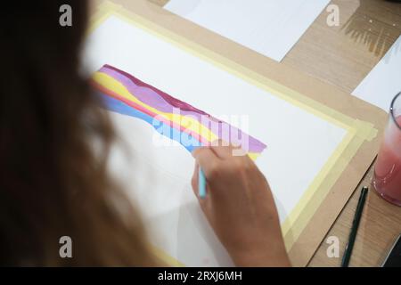 Gros plan des mains d'une jeune femme qui mélange des peintures acryliques sur une palette. Banque D'Images