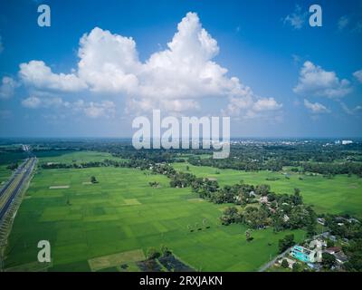 09.16.2023. Raiganj Bengale occidental Inde. Vue aérienne de dessus de la route nationale passant à travers des terres agricoles vertes Banque D'Images