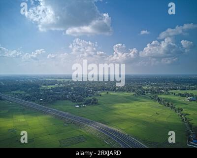 09.16.2023. Raiganj Bengale occidental Inde. Vue aérienne de dessus de la route nationale passant à travers des terres agricoles vertes Banque D'Images