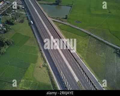 09.16.2023. Raiganj Bengale occidental Inde. Vue aérienne de dessus de la route nationale passant à travers des terres agricoles vertes Banque D'Images