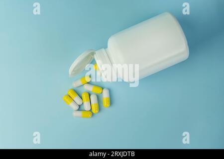 Capsules thérapeutiques jaunes de curcuma, pilules de vitamine de fines herbes ou médicaments pour le traitement sur fond bleu, médecine et concept de soins de santé, gros plan , haut Banque D'Images