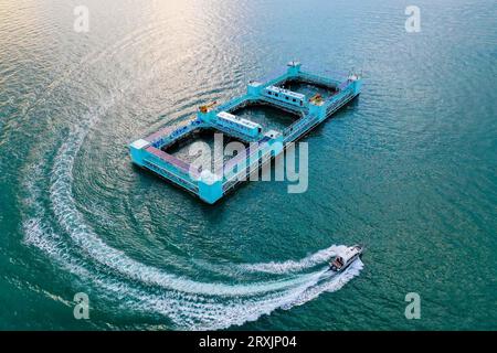 (230926) -- ZHANJIANG, 26 septembre 2023 (Xinhua) -- cette photo aérienne prise le 20 septembre 2023 montre un navire de transport naviguant près du 'Haiwei-2', une plate-forme aquacole semi-submersible intelligente dans la baie de Liusha à Zhanjiang, dans la province du Guangdong, dans le sud de la Chine. 'Haiwei-2' est un ranch marin géant transportant près de 1 millions d'alevins de pomfrette dorés d'environ 100 tonnes. Mesurant 86 mètres de long, 32 mètres de large et 16,5 mètres de haut, la plateforme géante possède une capacité de 30 000 mètres cubes d’eau pour l’aquaculture et peut récolter plus de 500 tonnes de poissons en un cycle. Equipé d'un électrice solaire Banque D'Images