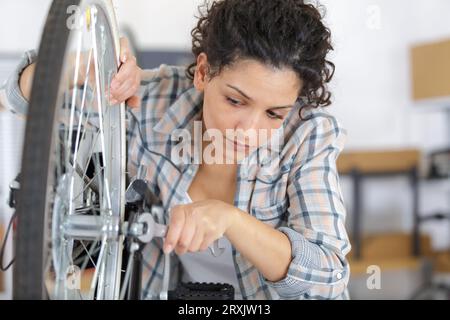 femme mécanicien serrant la pédale sur la bicyclette Banque D'Images