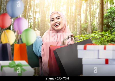 Une femme asiatique en voile présente un sac à provisions tout en célébrant une fête d’anniversaire. Concept de femme Joyeux anniversaire Banque D'Images