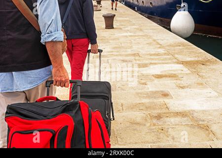 gros plan des passagers sur le paquebot transportant leurs bagages sur roues sur le quai Banque D'Images