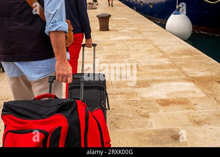 mains des passagers sur le paquebot transportant leurs bagages sur roues sur le quai Banque D'Images