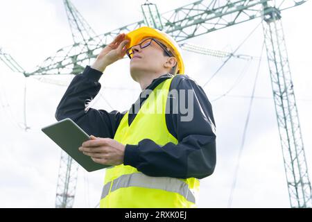 Concevoir une tablette numérique sur un arrière-plan de la tour de ligne électrique. Banque D'Images