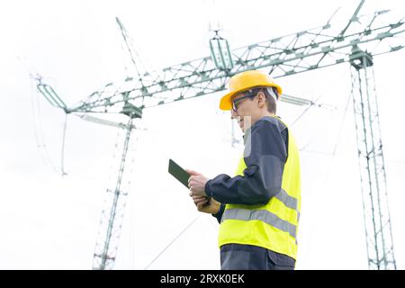 Concevoir une tablette numérique sur un arrière-plan de la tour de ligne électrique. Banque D'Images