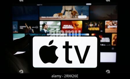 Personne tenant le smartphone avec le logo du service de streaming vidéo Apple TV plus sur l'écran en face du site Web. Concentrez-vous sur l'affichage du téléphone. Banque D'Images