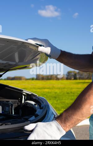 l'homme ouvre le capot d'une voiture. ouvrez le capot du véhicule à la main. Banque D'Images