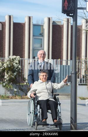 couple de personnes âgées attendant de traverser la route femme en fauteuil roulant Banque D'Images