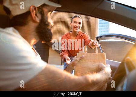 Homme de livraison remettant la boîte en carton de colis à Lady de l'automobile Banque D'Images