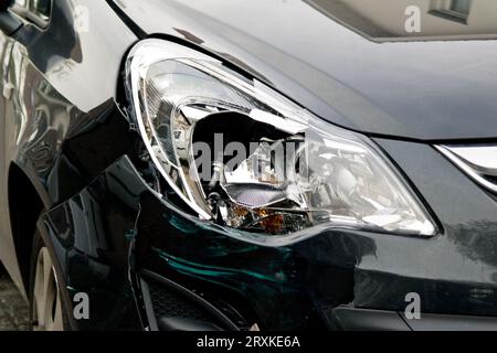 Petite voiture noire avec phare endommagé après collision Banque D'Images