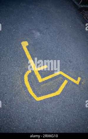 Panneau de fauteuil roulant peint en jaune sur la rue asphaltée, plan vertical Banque D'Images