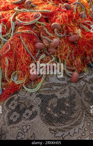 filets de pêche abstraits, filets de pêche séchant au soleil, filets de pêche orange posés sur et vieux tapis séchant dans un port méditerranéen. Banque D'Images