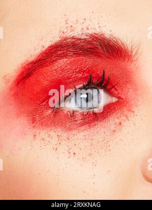 Gros plan de l'œil de jeune femme avec fard à paupières rouge Banque D'Images