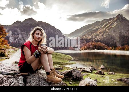Jeune femme hiker resting on rock au bord du lac Banque D'Images