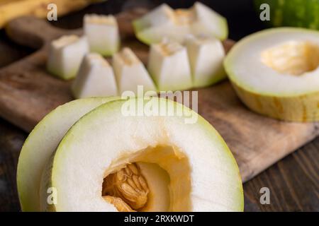 Pulpe de melon douce mûre divisée en petits morceaux, pulpe de melon mûre coupée sur une planche à découper dans la cuisine Banque D'Images