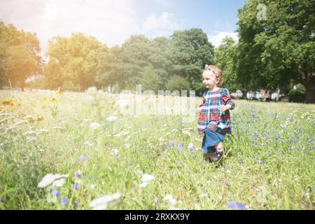 Enfant courant dans un champ de fleurs ensoleillé Banque D'Images