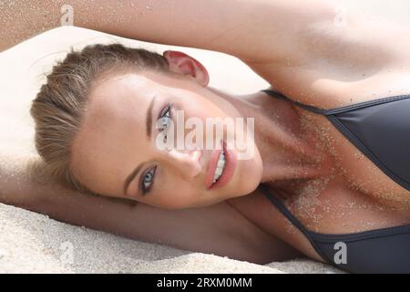 Portrait of young woman lying on sand Banque D'Images