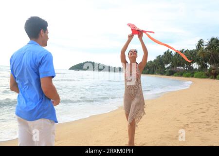 Jeune couple flying kite on beach Banque D'Images