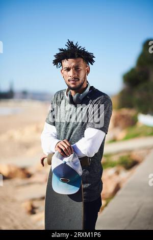 Young man leaning on skateboard Banque D'Images