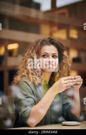 Young woman holding Coffee cup derrière la fenêtre cafe Banque D'Images