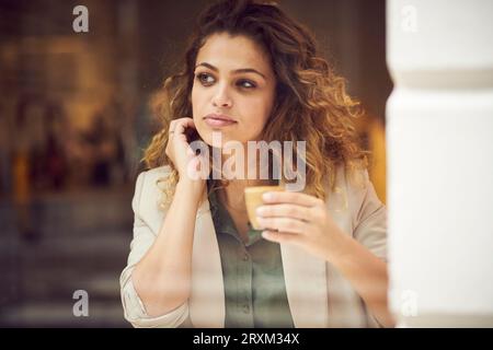 Young woman holding Coffee cup derrière la fenêtre cafe Banque D'Images