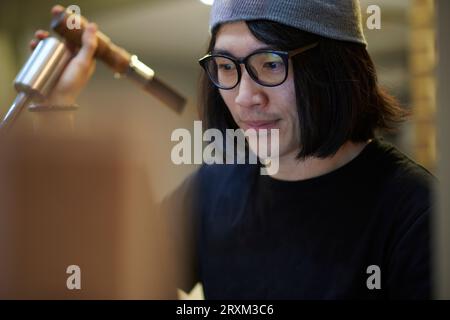 Jeune homme portant des lunettes utilisant une machine Banque D'Images