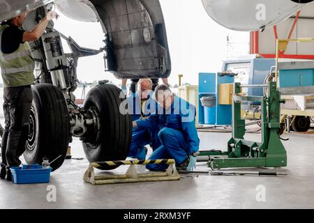 Des hommes travaillant sur la roue d'avion Banque D'Images