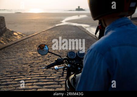 Motocycliste sur la rampe d'accès à la plage au coucher du soleil Banque D'Images