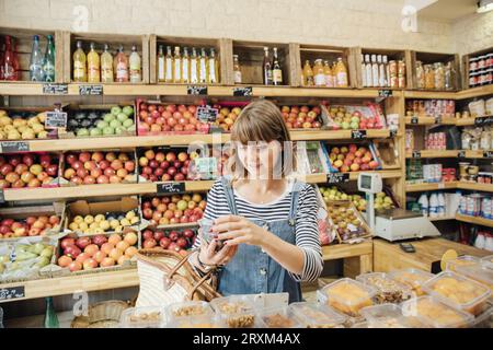 Jeune femme magasinant dans le magasin de fruits et légumes Banque D'Images