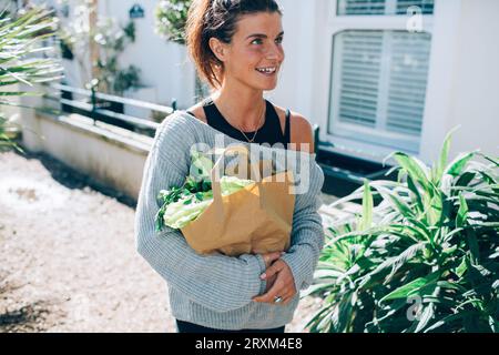 Femme adulte moyenne portant un sac en papier de légumes Banque D'Images