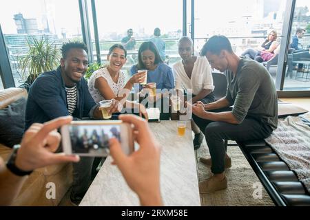 Collègues posant pour photographier avec boissons Banque D'Images