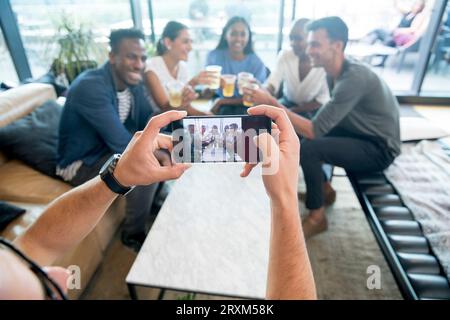 Collègues posant pour photographier avec boissons Banque D'Images