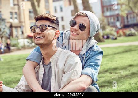 Gay couple sitting in park Banque D'Images