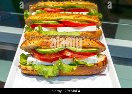 Vitrine avec un sandwich végétalien de légumes dans un café. Pain à emporter avec fromage, tomates, concombres et feuilles vertes et salade Banque D'Images