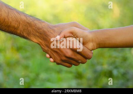 Concept de serrer la main. Amical faire une affaire avec une poignée de main de deux mains sur fond de plantes de légumes à la ferme. Concept de secouage manuel. Ami Banque D'Images