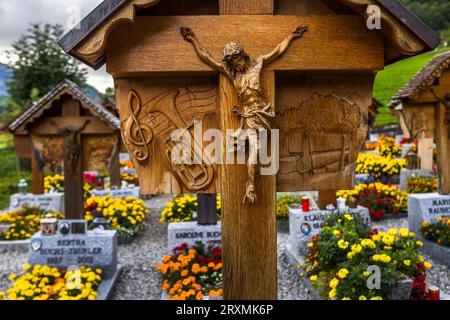 Une croix funéraire à Jaun représente une clé de sol avec un porteur de partie et un instrument de cuivres dans son relief gauche et un paysage montagneux avec un objet qui ne peut être clairement identifié à droite, probablement la musique de fanfare comme passe-temps de la personne y enterrée. Chacune des croix en bois sculptées individuellement sur le cimetière derrière l'église Saint-Étienne porte un tel relief représentant la profession ou le passe-temps de la personne enterrée en dessous, une tradition commencée en 1948 par le sculpteur autodidacte Walter Cottier et poursuivie depuis 1988 par son cousin Reynold Boschung. Des parterres de fleurs jaunes et orange entourent Banque D'Images