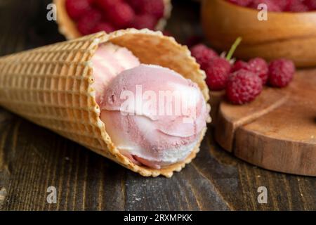 Cône de gaufrage avec crème glacée rose blanche et framboises, crème glacée à la framboise dans un cône de gaufre Banque D'Images