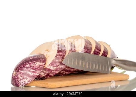 Une aubergine juteuse coupée en morceaux et un couteau en métal sur une planche de cuisine en bambou, macro, isolé sur fond blanc. Banque D'Images