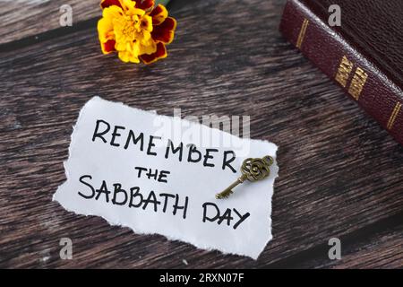 Rappelez-vous le jour du Sabbat, citation manuscrite avec clé ancienne, bible sainte, et fleur sur bois. Repos biblique, obéissance chrétienne à Dieu Jésus-Christ. Banque D'Images