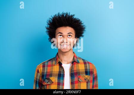 Portrait de toothy beaming Guy avec permanente coiffure habillée chemise à carreaux look à la vente espace vide isolé sur fond de couleur bleue Banque D'Images