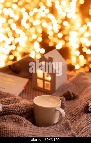 Livre photo tricoté pull chaud tasse café petite bougie Noël guirlande fond bokeh photo atmosphérique hiver Banque D'Images