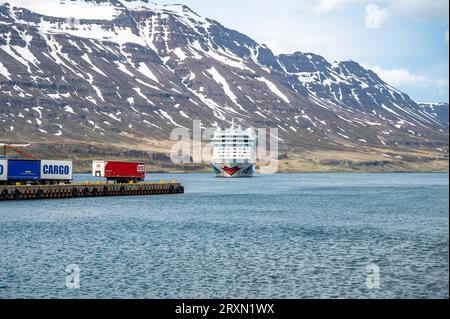 Aida Bella bateau de croisière au fjord de Seydisfjordur, Islande, vue de la distance avec port à l'avant et chaîne de montagnes de neige à l'arrière Banque D'Images