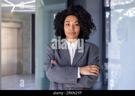 Portrait de femme d'affaires afro-américaine sérieuse réussie, patron en costume d'affaires regardant concentré à la caméra avec les bras croisés, travailleur financier féminin à l'intérieur du bureau au lieu de travail. Banque D'Images