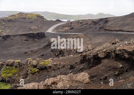 Route sinueuse à travers le paysage volcanique, près du lac Kleifarvatn sur une journée d'été brumeuse et couverte en Islande Banque D'Images